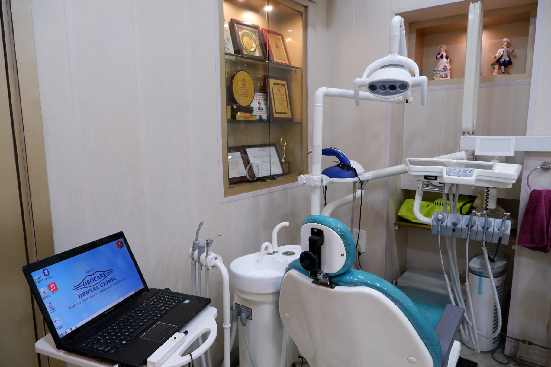 Dental chair beside a display of awards and certifications at OroCare Dental Clinic, Bhowanipur