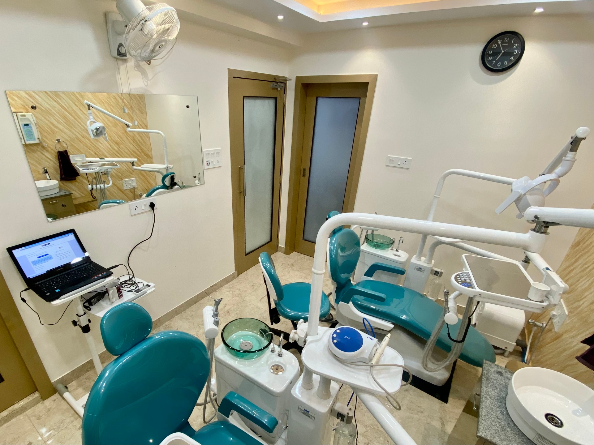 Dental operatory with large mirror wall and modern teal chair at OroCare Dental Clinic, Mukundapur