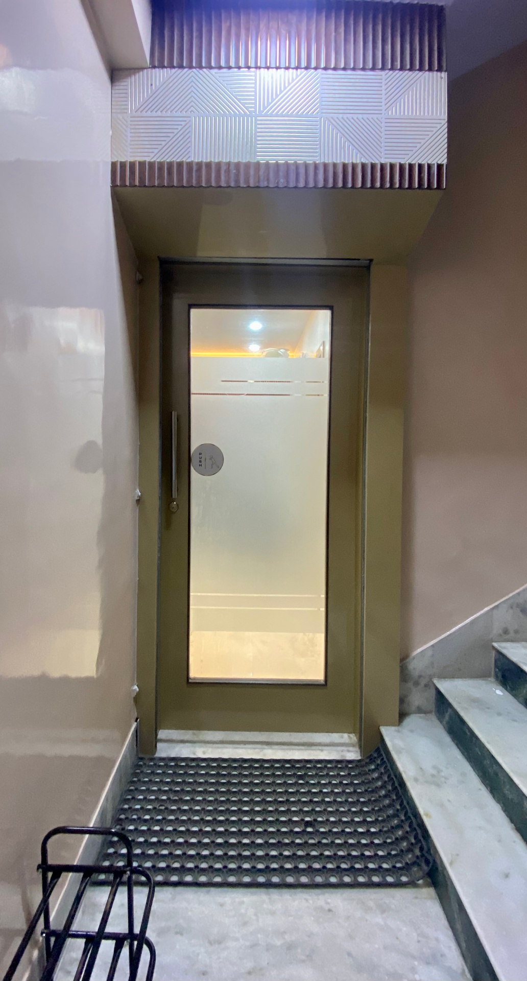 Glass push-door entrance to OroCare Dental Clinic at the top of the M.B. Tower staircase, Mukundapur