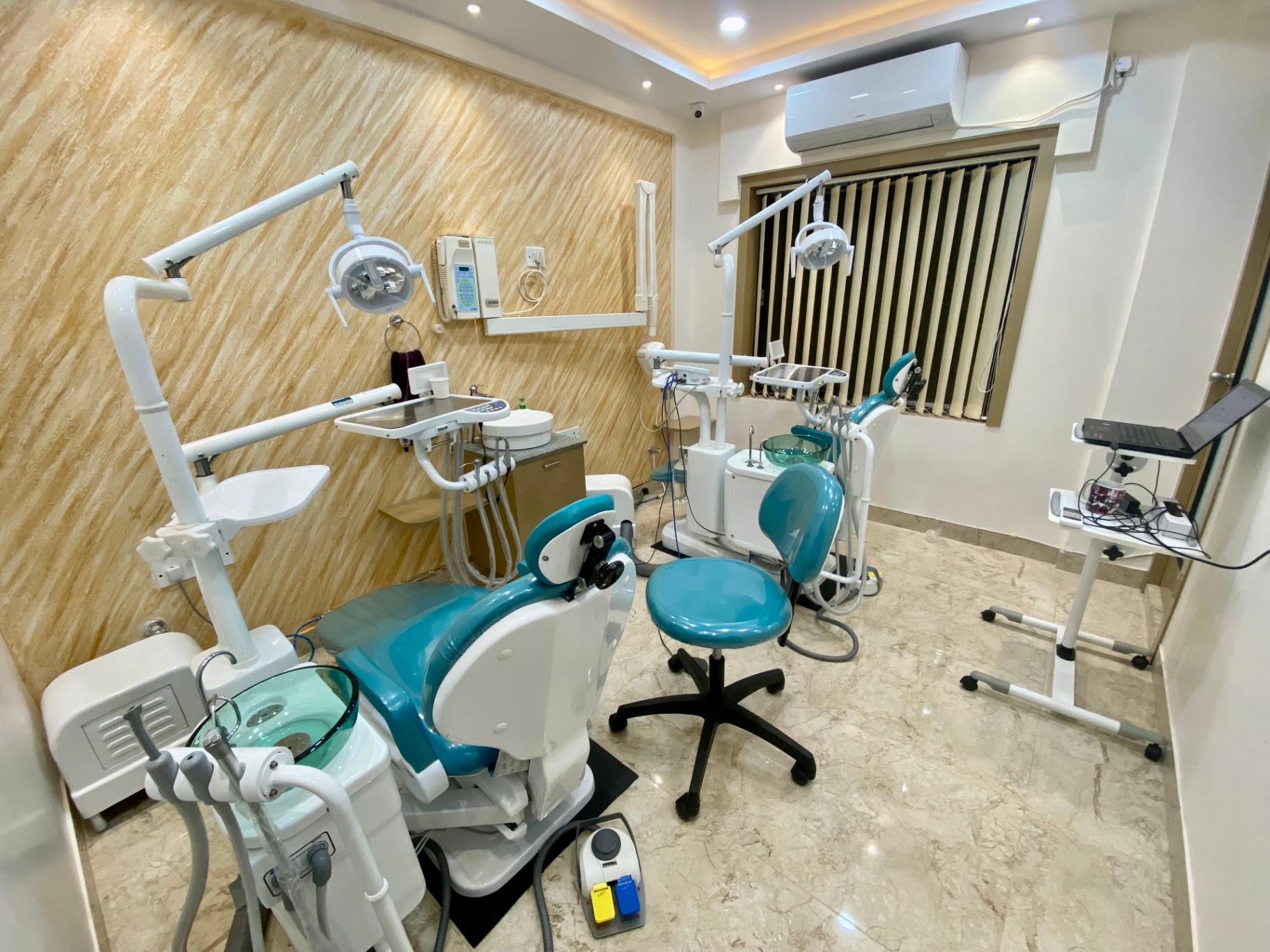 Twin dental chairs with overhead lights and wood-panelled wall at OroCare Dental Clinic, Mukundapur