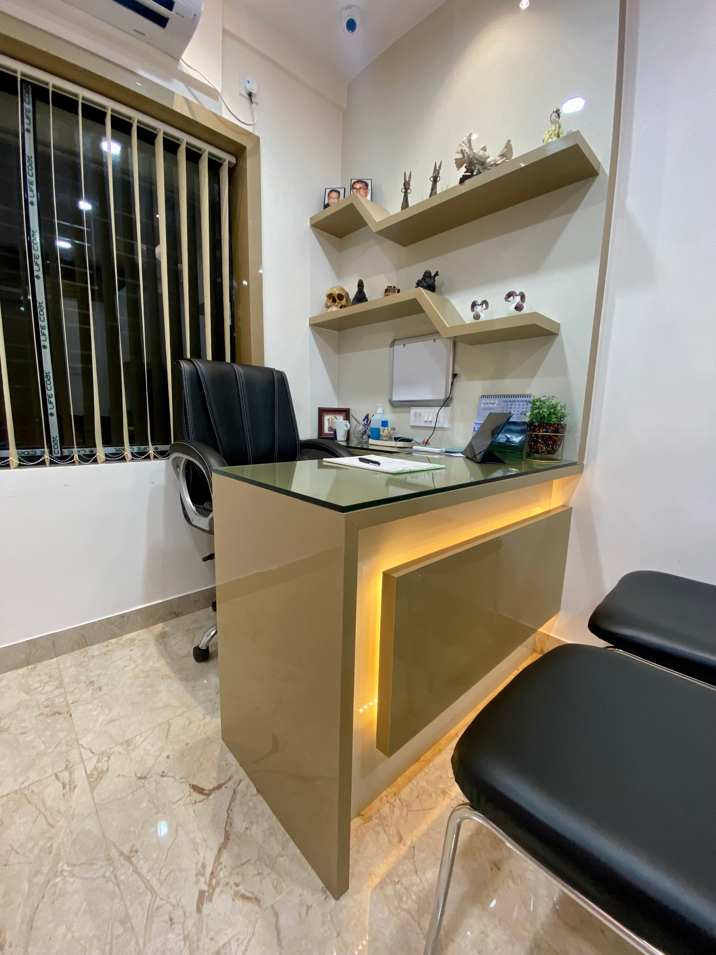 Consultation desk with backlit cabinetry and shelving inside OroCare Dental Clinic, Mukundapur